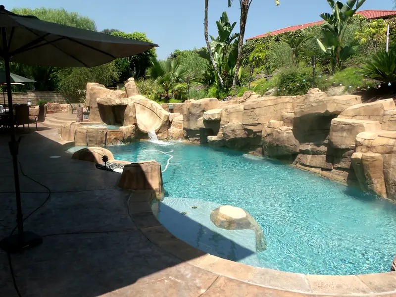 Freeform pool with a sculpted rock grotto, waterfall, and slide
