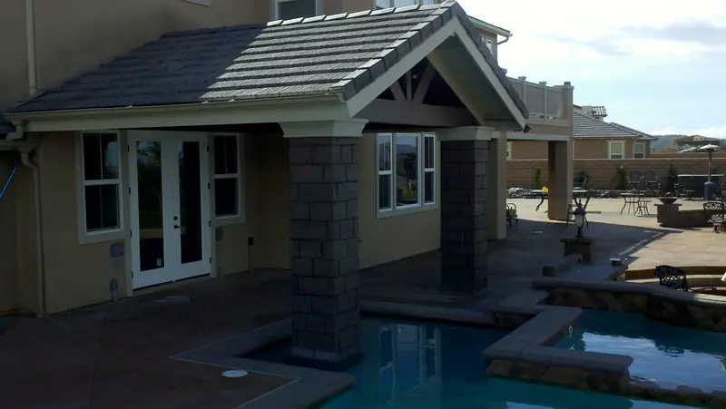 Patio cover with stone columns over a pool and spa