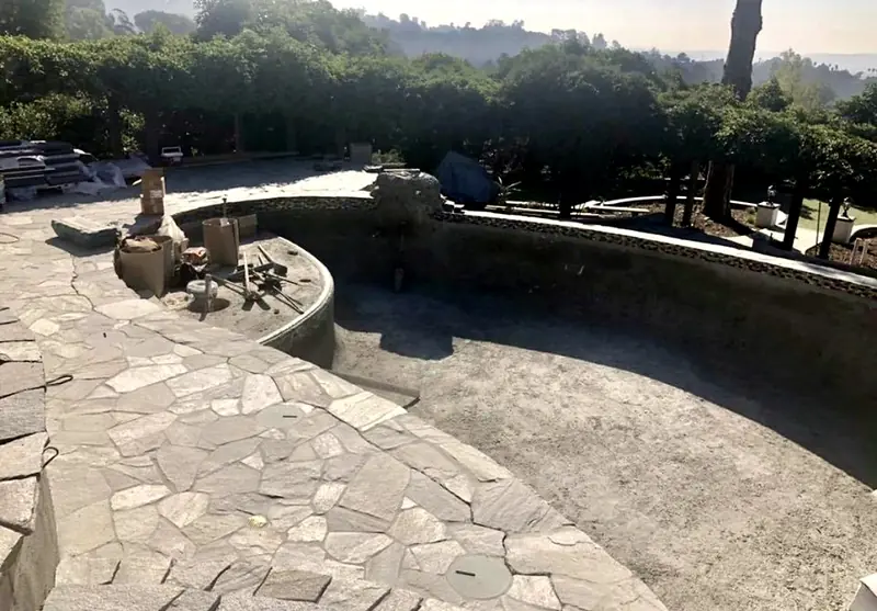 Remodel day one: the old pool shell exposed while new flagstone decking goes down